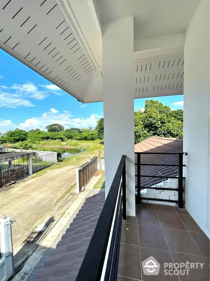 Charming balcony with scenic view of lush greenery and clear blue sky, perfect for relaxation.