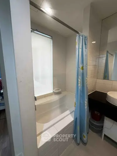 Cozy bathroom with bathtub and floral shower curtain, featuring modern sink and mirror.