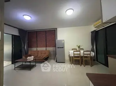 Spacious living room with modern furniture and dining area, featuring large windows and sleek flooring.