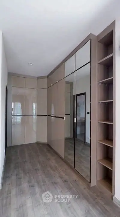 Spacious modern storage area with sleek mirrored cabinets and open shelving.