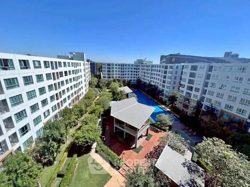 Stunning aerial view of modern apartment complex with lush gardens and inviting pool area.