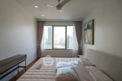 Modern bedroom with city view, featuring a large window and elegant decor.