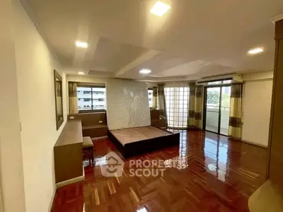 Spacious living room with polished wooden floors and large windows offering natural light.