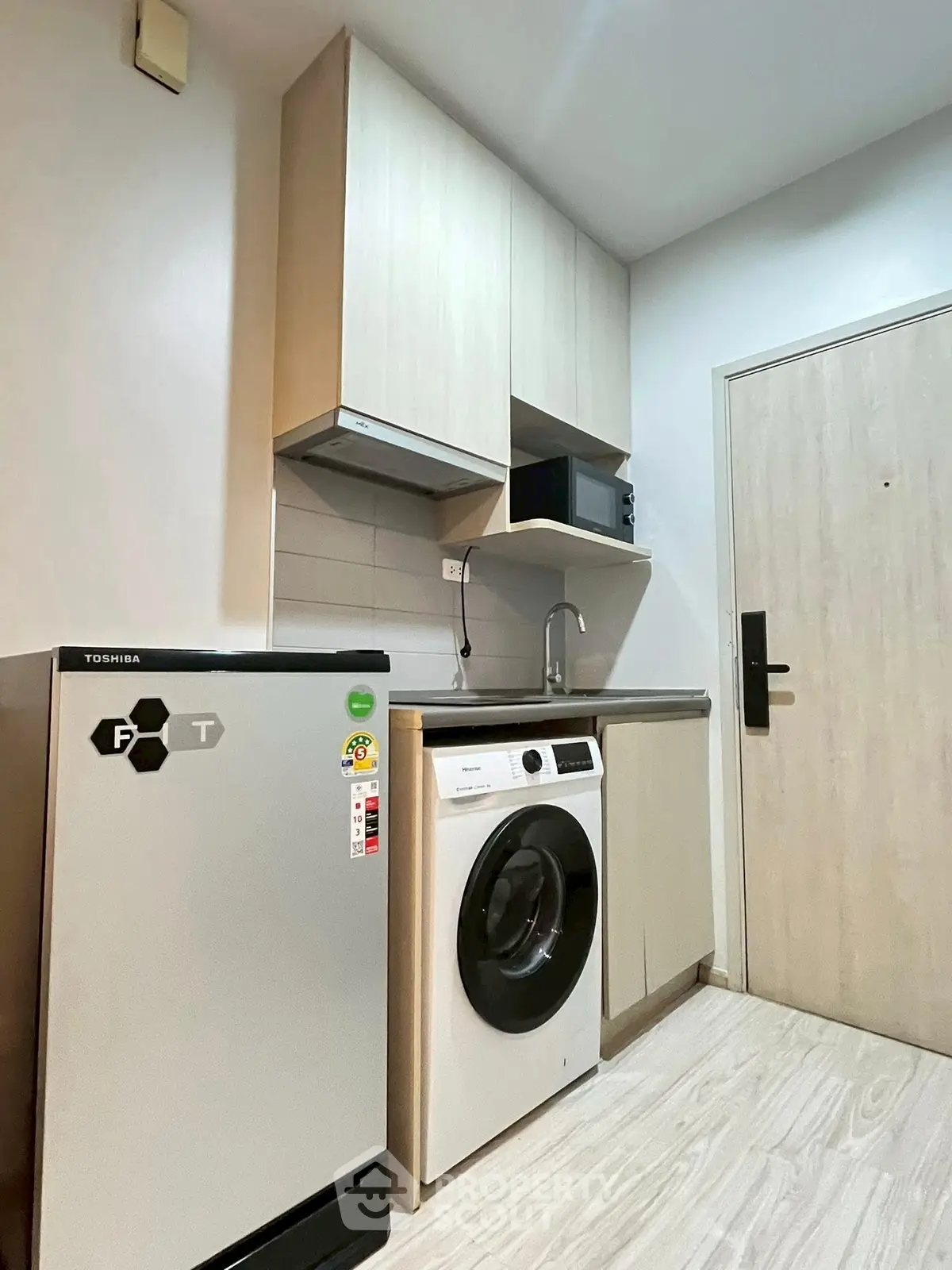 Compact kitchen with washing machine and fridge in modern apartment
