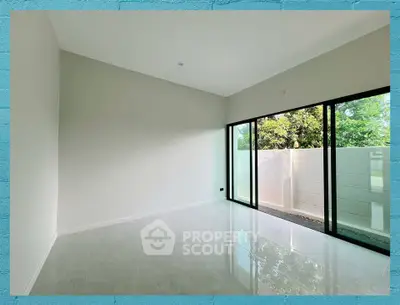 Spacious empty room with large glass doors leading to a private garden, perfect for customization.