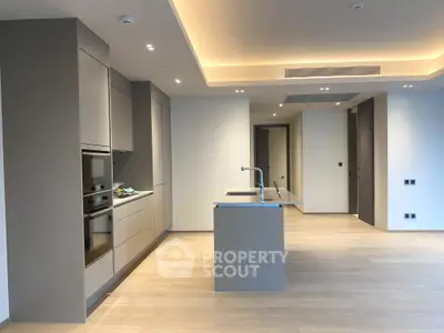 Modern open-plan kitchen with sleek cabinetry and island in luxury apartment.