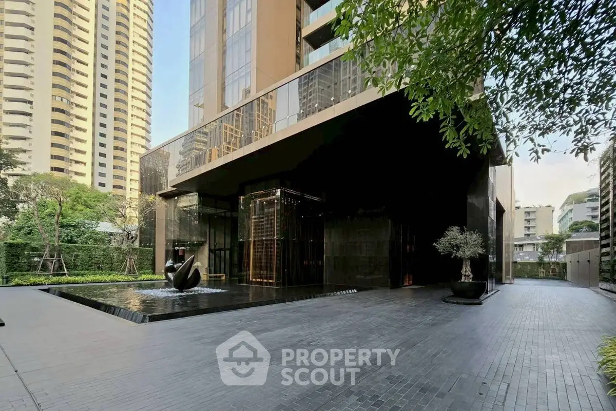 Luxurious modern building entrance with sleek design and water feature in prime urban location.