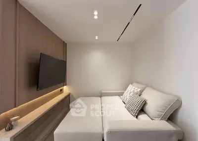 Modern living room with sleek design and cozy sofa, featuring a wall-mounted TV and ambient lighting.