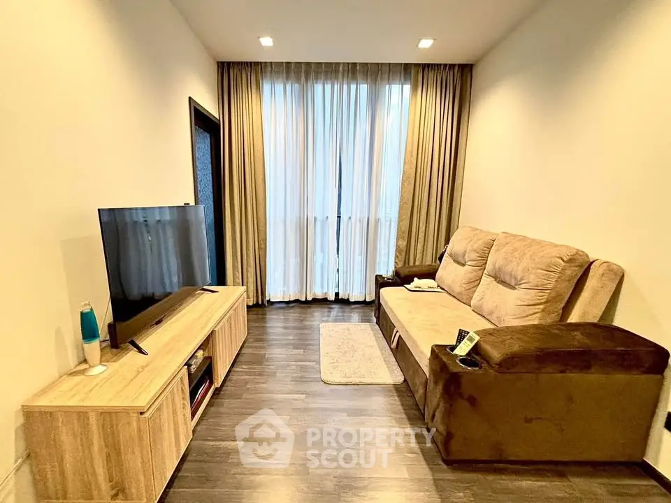 Cozy living room with modern decor, featuring a plush sofa and large flat-screen TV, perfect for relaxation.