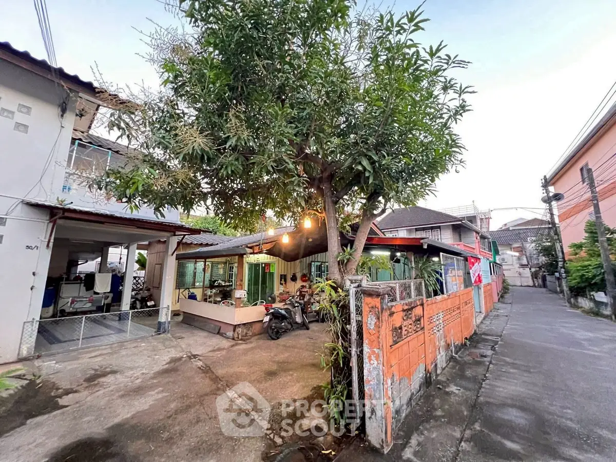 Charming urban house with spacious driveway and lush tree in front yard.