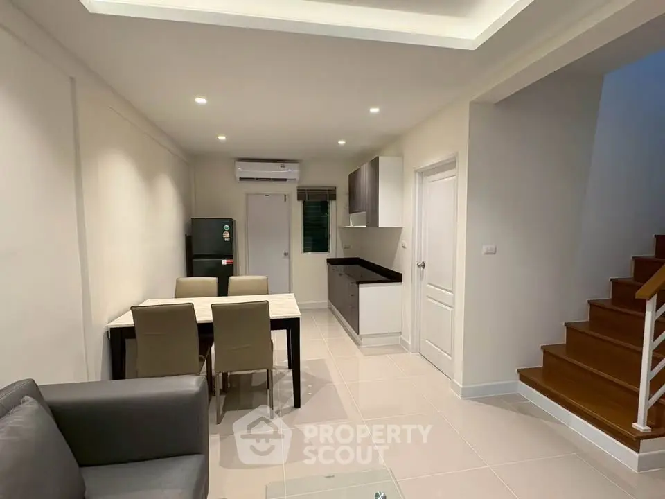 Modern open-plan living and dining area with sleek kitchen and staircase.