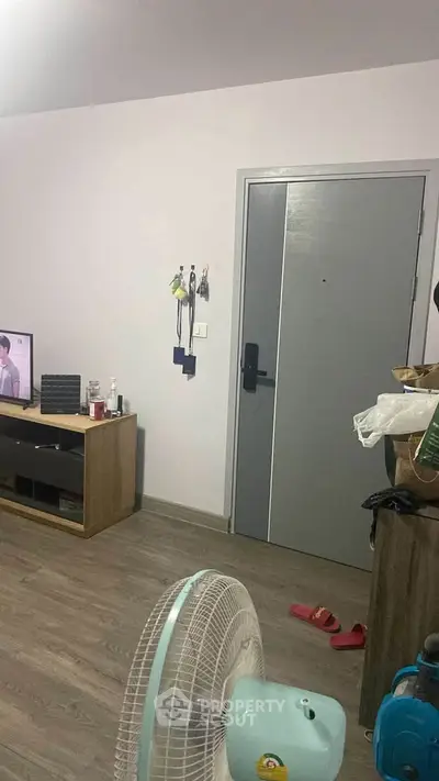 Cozy living room with modern decor and wooden flooring, featuring a TV and stylish furniture.