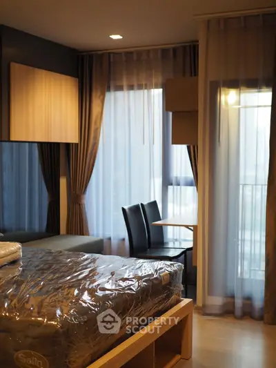 Modern bedroom with floor-to-ceiling windows and elegant curtains, featuring a cozy seating area and stylish decor.