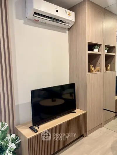 Modern living room with sleek TV stand and air conditioning unit, featuring stylish wooden cabinetry.