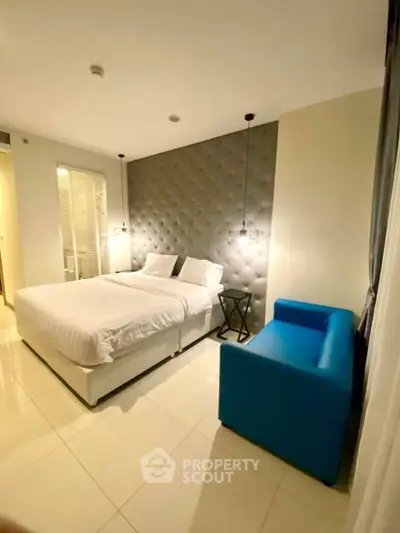 Modern bedroom with stylish decor and vibrant blue sofa