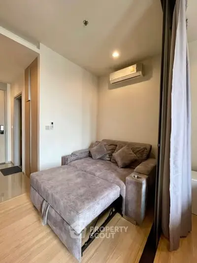 Cozy living room with plush gray sofa and modern air conditioning unit.