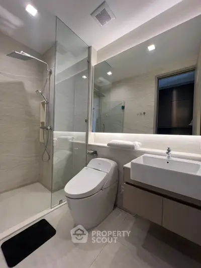 Modern bathroom with glass shower and sleek fixtures in luxury apartment.
