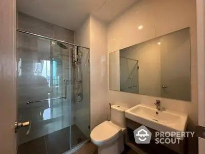 Modern bathroom with glass shower and sleek fixtures in contemporary apartment.