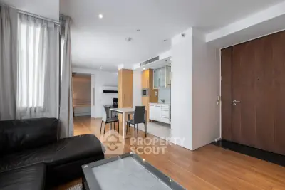 Modern open-plan living room with sleek kitchen and dining area, featuring hardwood floors and contemporary furniture.