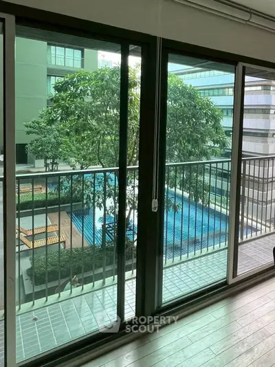 Modern apartment balcony with pool view and lush greenery