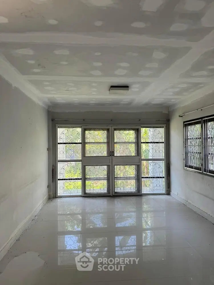 Spacious empty room with large windows and glossy tiled floor