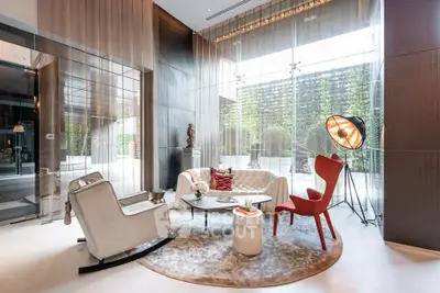 Luxurious modern living room with stylish furniture and floor-to-ceiling windows offering garden views.