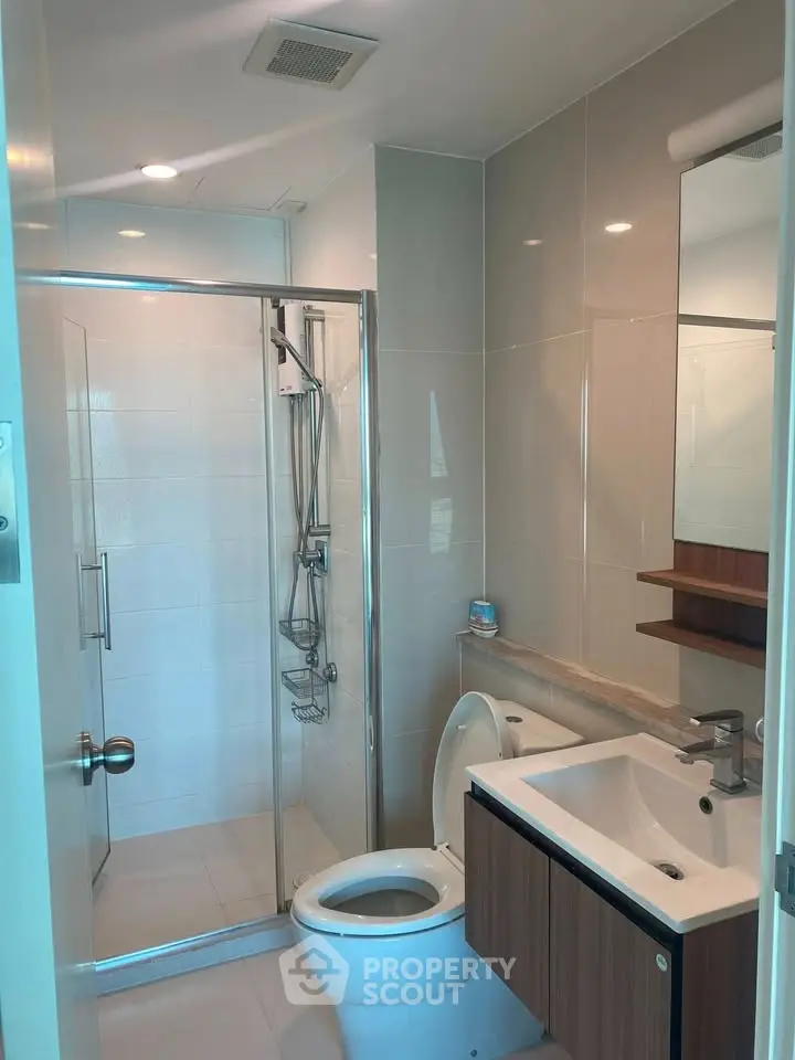 Modern bathroom with glass shower and sleek fixtures in a contemporary apartment.
