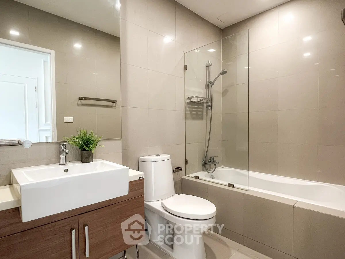 Modern bathroom with sleek fixtures and glass-enclosed bathtub in a stylish apartment.