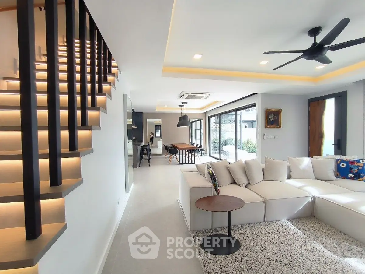 Modern open-plan living room with stylish staircase and large windows