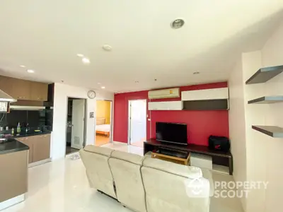 Spacious living room with modern open kitchen layout, sleek countertops, and vibrant red accent walls, perfect for entertaining and comfortable living.