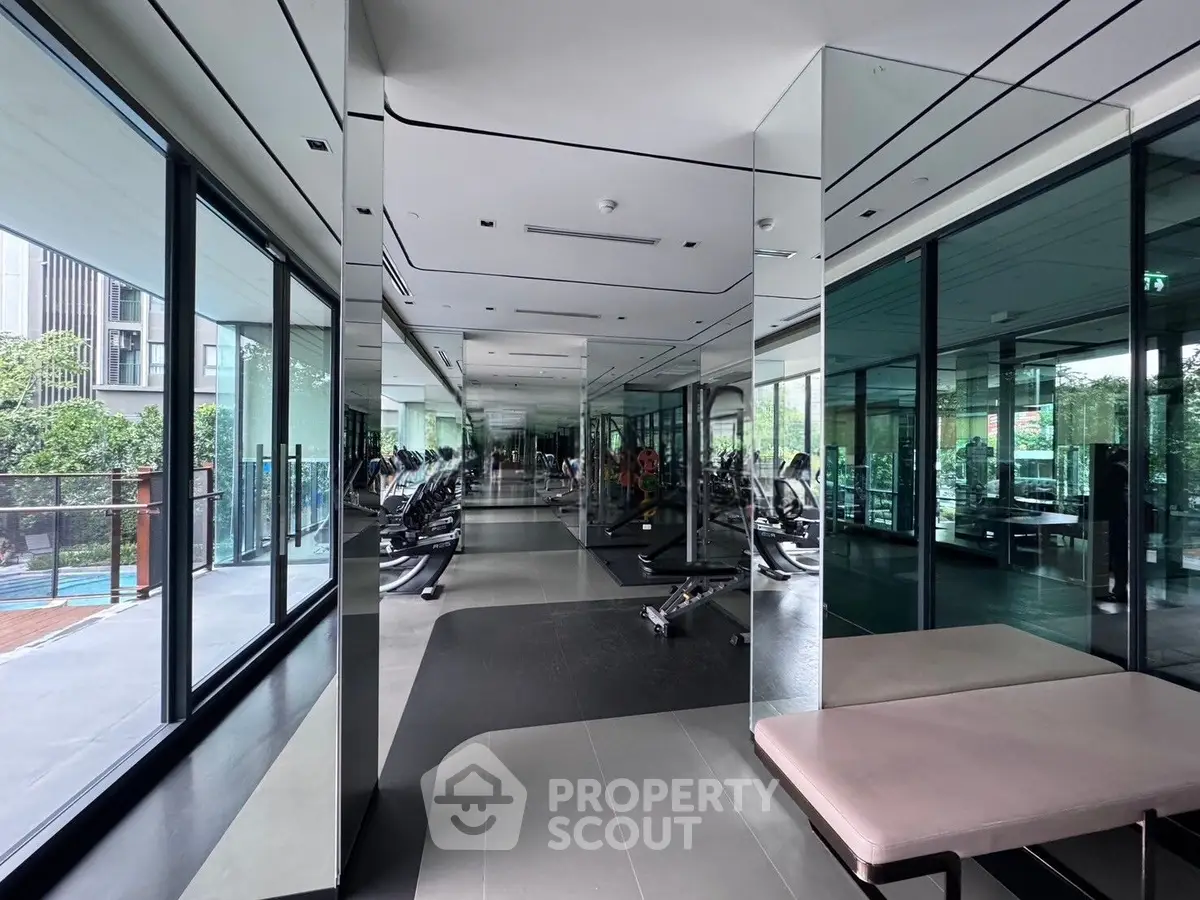 Modern gym with mirrored walls and state-of-the-art fitness equipment in luxury apartment complex.