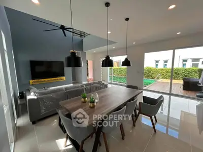 Modern living room with stylish dining area and pool view, featuring sleek furniture and abundant natural light.