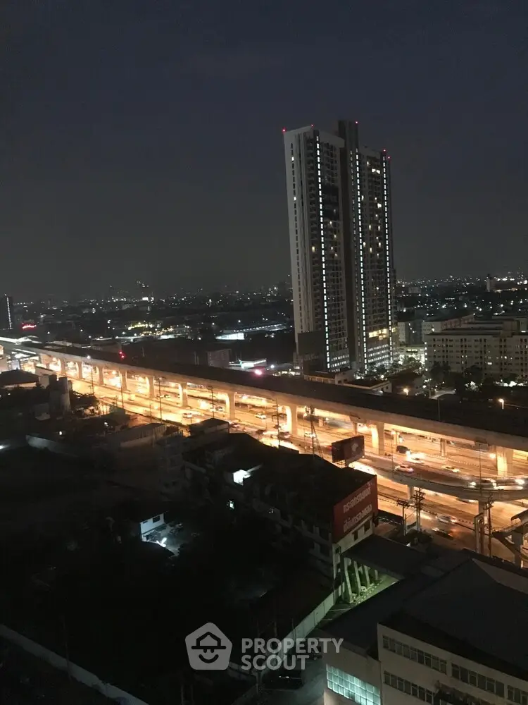 Stunning night view of cityscape with illuminated highway and towering skyscraper.