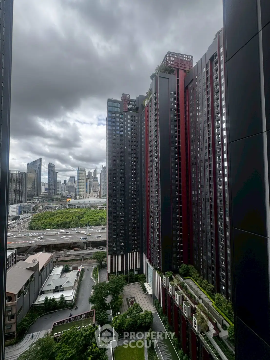 Stunning cityscape view from high-rise building with lush greenery and modern architecture.