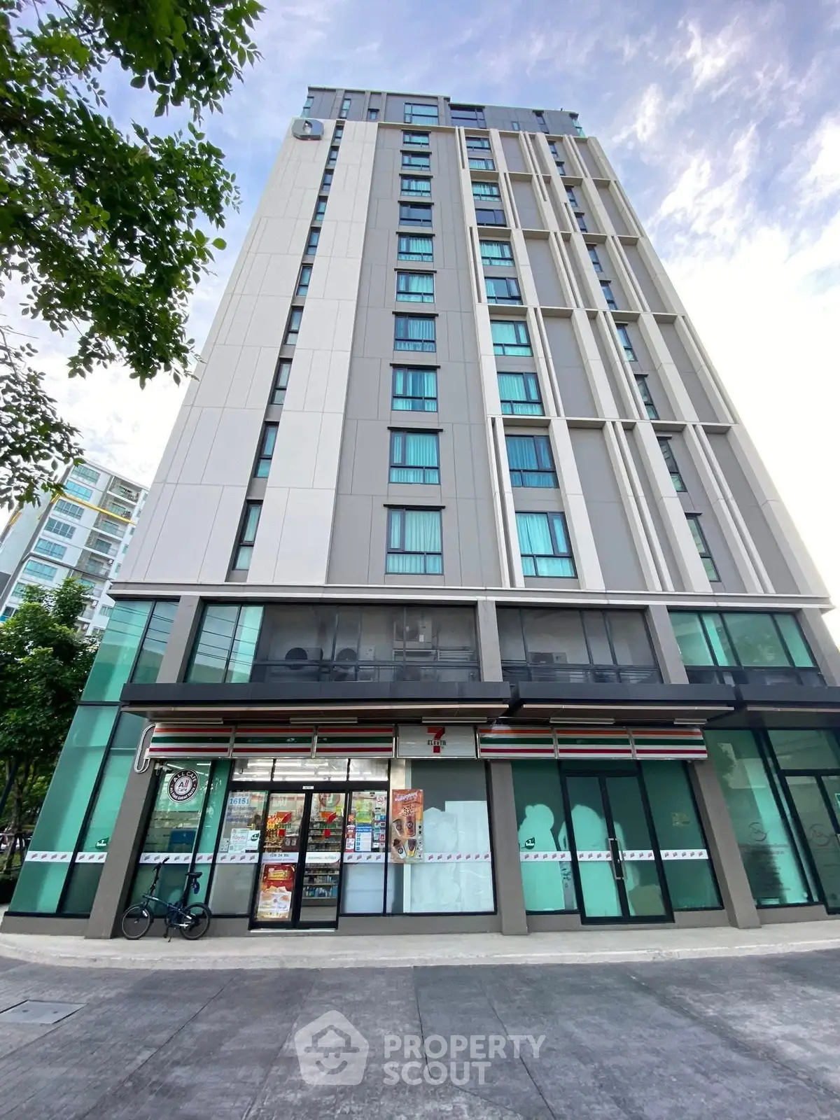 Modern high-rise building with ground-floor retail space and sleek glass facade.