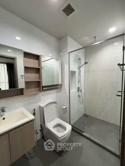 Modern bathroom with glass shower and sleek fixtures in contemporary apartment.