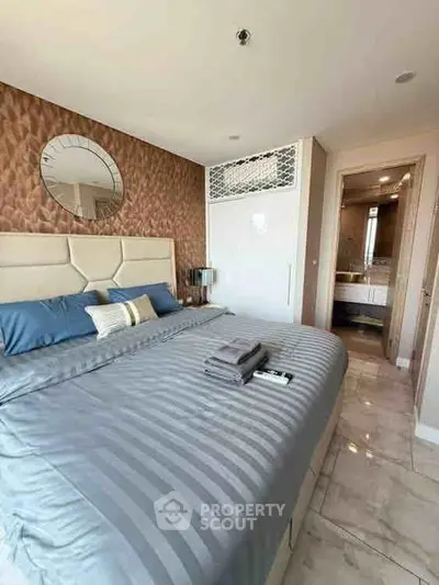 Luxurious bedroom with elegant decor and ensuite bathroom in modern apartment.