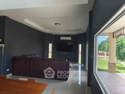 Spacious living room with modern decor and large windows overlooking a lush garden.