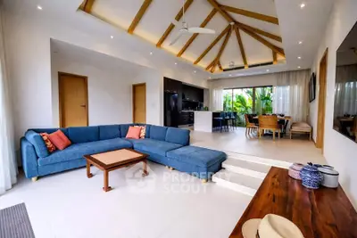 Spacious modern living room with vaulted ceiling and open layout, featuring a large blue sectional sofa and dining area.