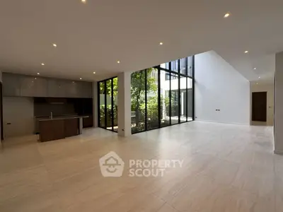 Spacious modern living room with open kitchen and large windows overlooking garden.