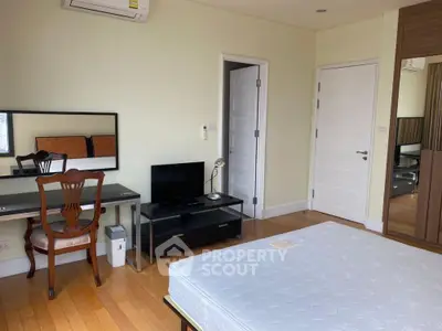 Spacious bedroom with hardwood floors, modern furniture, and ample natural light.