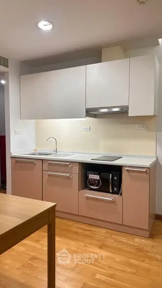 Modern kitchen with sleek cabinetry and built-in appliances, featuring a minimalist design and wooden flooring.