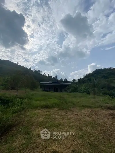 Modern house nestled in lush green landscape with scenic mountain backdrop.
