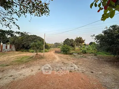 Expansive plot of land with lush greenery and clear sky, perfect for development.