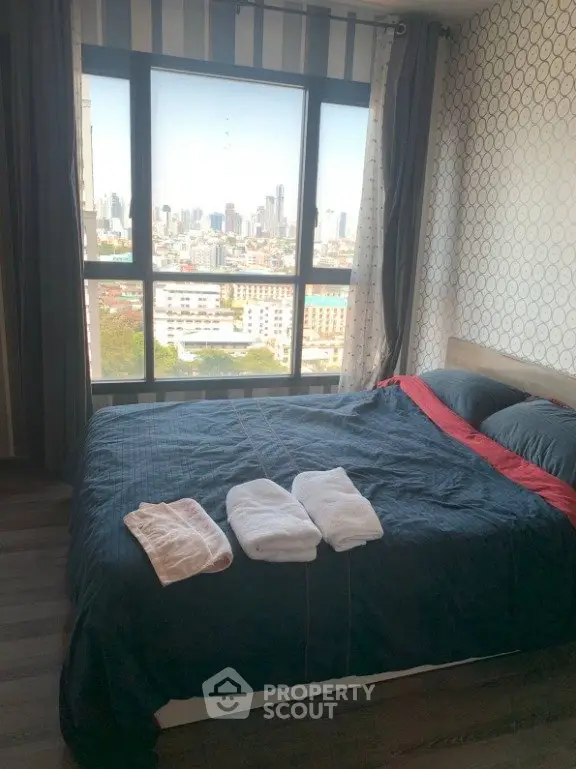 Modern bedroom with city view, featuring stylish decor and large windows for natural light.