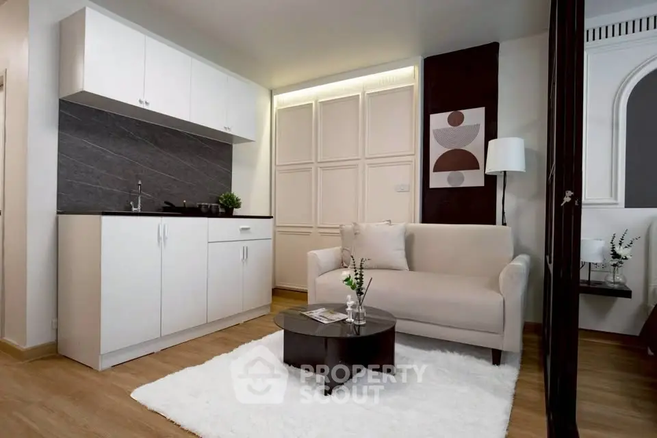 Modern living room with compact kitchen, cozy sofa, and stylish decor in a contemporary apartment.