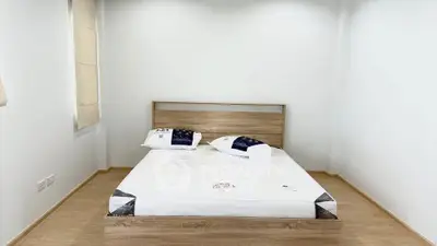 Spacious minimalist bedroom with wooden flooring and modern bed frame, perfect for relaxation.