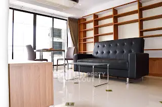 Modern living room with sleek black sofa and large windows in a stylish apartment.