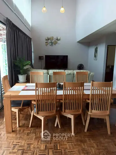Spacious dining area with wooden furniture and high ceiling, perfect for family gatherings.