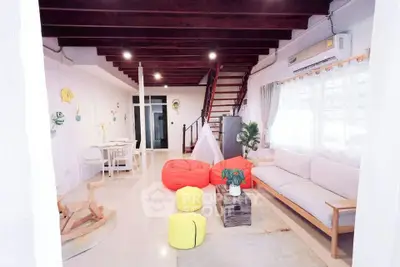 Spacious living room with modern decor and vibrant bean bags, featuring a cozy seating area and stylish staircase.